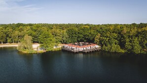 Een vakantiehuis aan het meer, met een steiger die het water in reikt, omgeven door dicht bos.