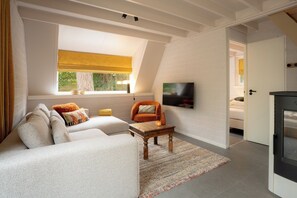 Una sala de estar moderna con un sofá modular, una mesa de centro de madera y un televisor montado en la pared.