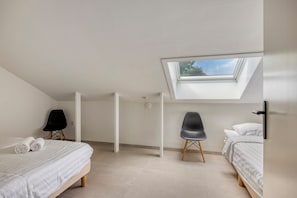 A bedroom with a skylight, two beds, a chair, and a wardrobe. - Hoeve de Eik, which sleeps eight, is a spacious and cosy apartment on the top floor, ideal for families or small groups. (Epen)