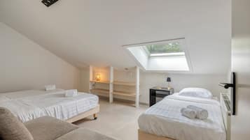 Een moderne slaapkamer met twee bedden, een dakraam en een klein bureau met een lamp.