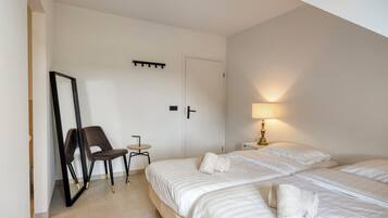 Een hotelkamer met twee bedden, een stoel, een tafeltje, een spiegel en een lamp.