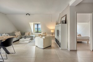 A modern living room with a sofa, a coffee table, and a TV stand. - Hoeve de Eik, which sleeps eight, is a spacious and cosy apartment on the top floor, ideal for families or small groups. (Epen)