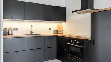 A modern kitchen with dark cabinetry, a stainless steel sink, a toaster, and a built-in oven.