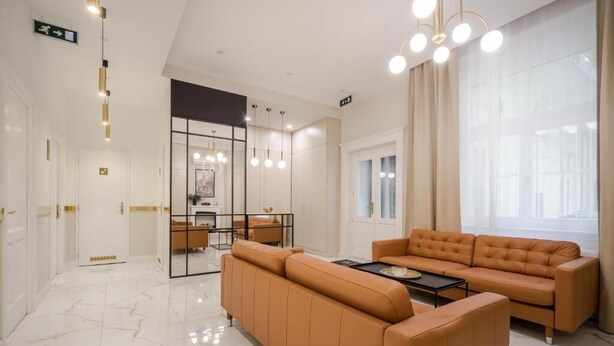 A modern living room with a sofa and a coffee table, a dining area with a table and chairs, and a large window with curtains. - Budapest Cereja Boutique (Budapest)
