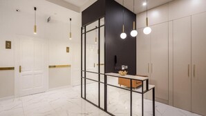 A modern interior with a marble floor, a black partition with glass panels, and a wooden cabinet with a bowl on top. - Budapest Cereja Boutique (Budapest)