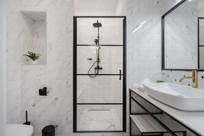 A modern bathroom with a glass-enclosed shower, a white sink, and a marble-tiled wall. - Budapest Cereja Boutique (Budapest)