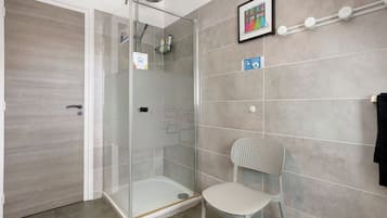 Une salle de bain moderne avec une douche à parois de verre, une chaise blanche et un porte-serviettes.