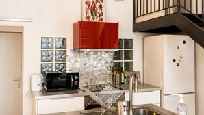 A modern kitchen with a stainless steel countertop, a built-in microwave, a sink, and a red cabinet. - Former Loft Studio, 105 m² • Air Conditioning • Vaulted Cellar • The Heart of Aix's Historic Center (Aix-en-Provence)