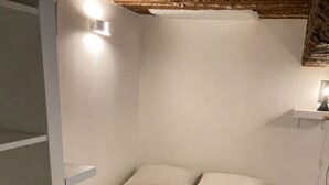 A bedroom with a bed, built-in shelving, and a bedside table with a lamp. - Former Loft Studio, 105 m² • Air Conditioning • Vaulted Cellar • The Heart of Aix's Historic Center (Aix-en-Provence)
