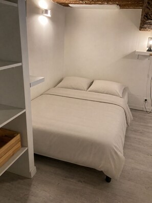 A bedroom with a bed, built-in shelving, and a bedside table with a lamp. - Former Loft Studio, 105 m² • Air Conditioning • Vaulted Cellar • The Heart of Aix's Historic Center (Aix-en-Provence)