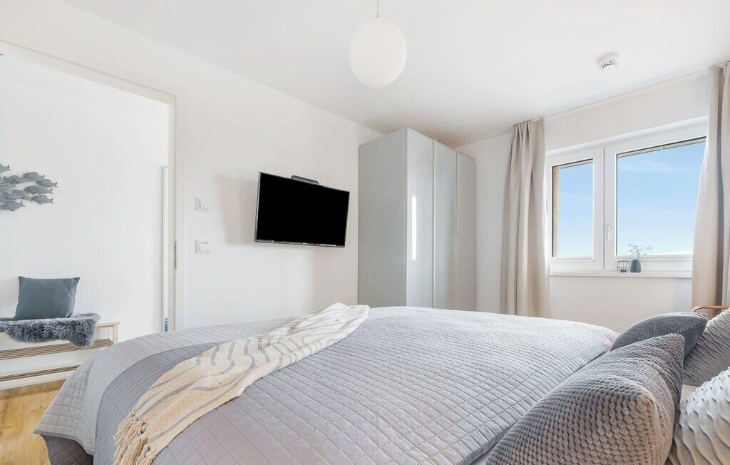 Une chambre à coucher avec un lit, une télévision, une armoire et une fenêtre.