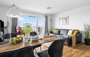 Ein modernes Wohnzimmer mit Essbereich, einer Sofagarnitur und einem großen Fenster mit Blick.