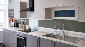Una cucina moderna con mobili grigi, un lavello in acciaio inossidabile e un forno a microonde.