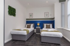 Une chambre d’hôtel avec deux lits, une table de chevet, une lampe et une fenêtre.