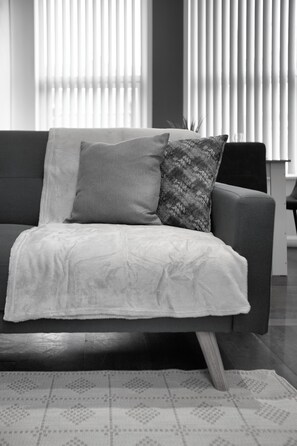A modern living room with a sofa, two pillows, and a patterned rug. - South Pier Apartment 3 (Blackpool)