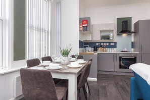 A modern kitchen with a dining area, a microwave, and a fire blanket sign. - South Pier Apartment 3 (Blackpool)