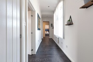 A hallway with white walls, a dark wooden floor, and a door at the end. - South Pier Apartment 3 (Blackpool)