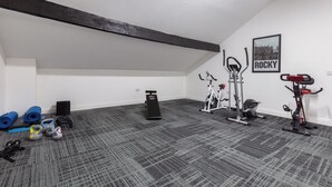Ein Heimfitnessraum mit Trainingsgeräten, Yogamatten und Kurzhanteln.