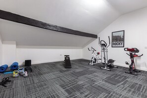 Ein Heimfitnessraum mit Trainingsgeräten, Yogamatten und Kurzhanteln.