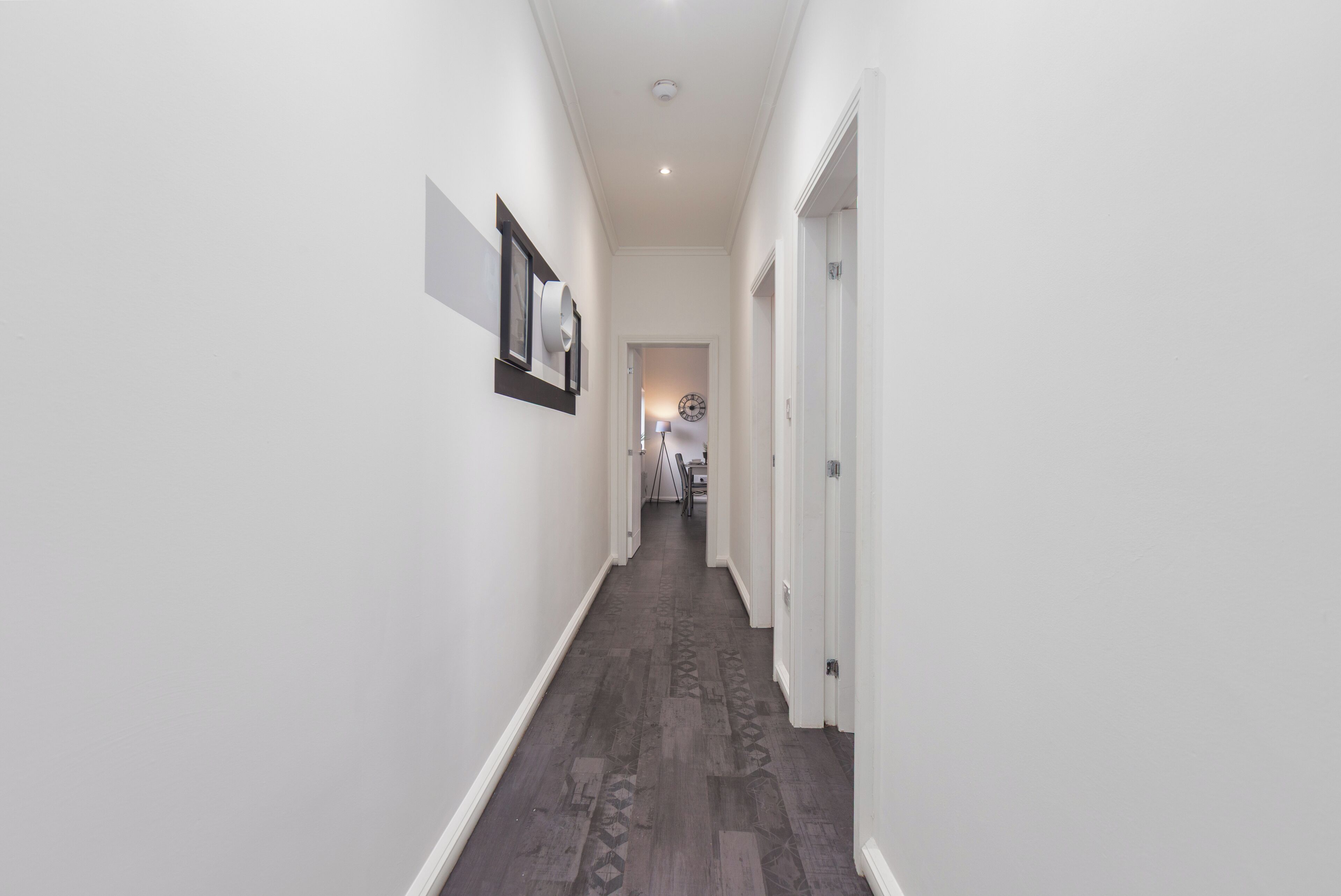 A narrow hallway with white walls and a patterned floor.