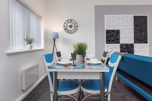 Een moderne eetruimte met een tafel, stoelen, een klok en een bank.
