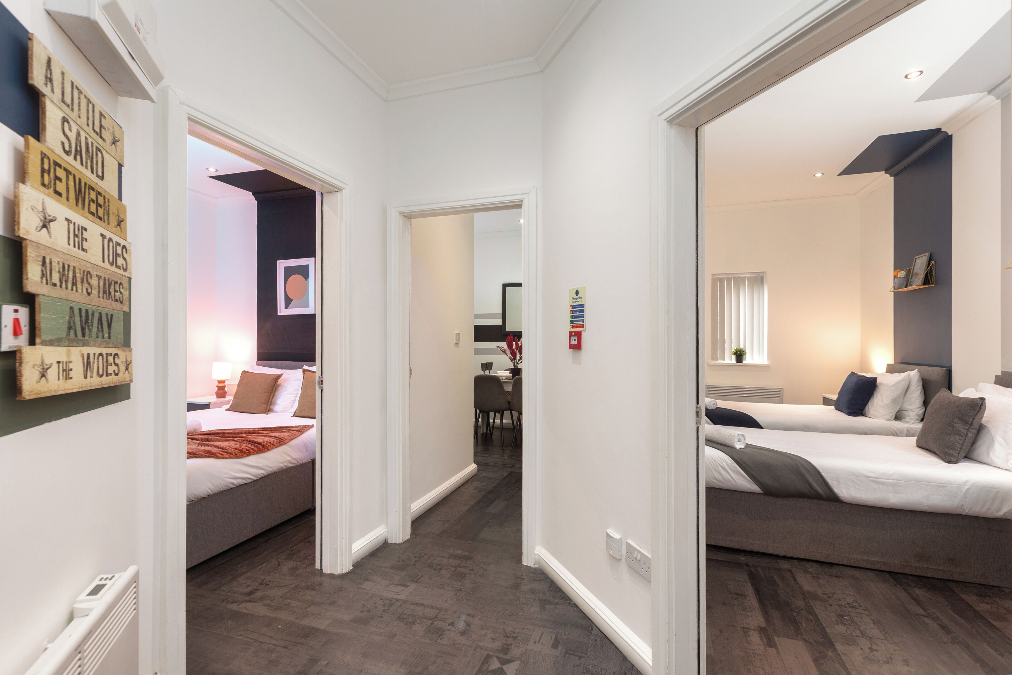 A hotel room with a bed, a bedside table, and a wall-mounted sign.