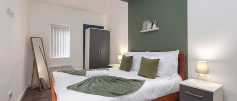 Un dormitorio con cama, mesita de noche, armario y ventana con persianas.