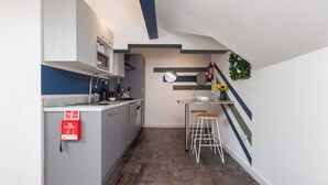 A compact kitchen with a central island, bar stools, and a fire extinguisher. - South Pier Apartment 7 (Blackpool)