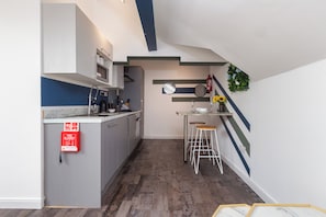 A compact kitchen with a central island, bar stools, and a fire extinguisher. - South Pier Apartment 7 (Blackpool)