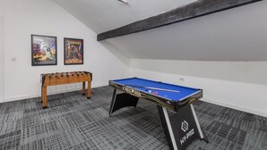 A room with a pool table, a foosball table, and two movie posters on the wall. - South Pier Apartment 7 (Blackpool)