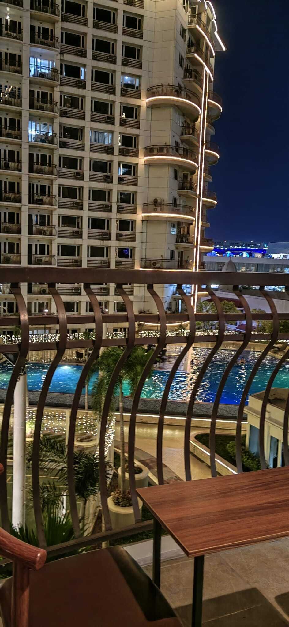 A multi-story hotel with balconies and a pool area.