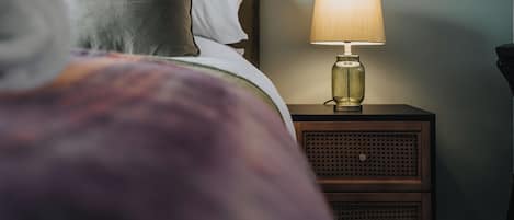 A bed with pillows, a bedside lamp, and a nightstand with drawers.