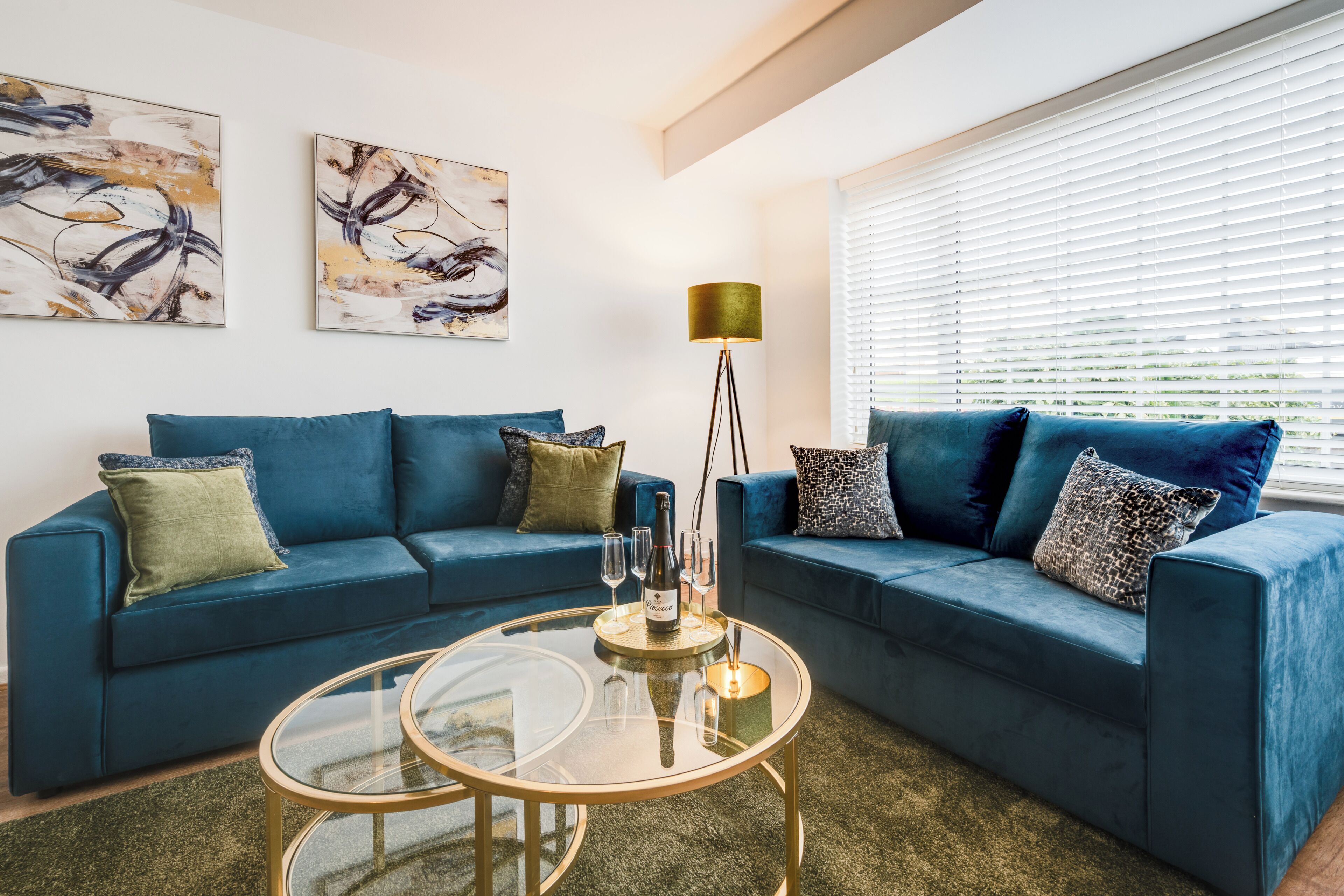A modern living room with two sofas, a glass coffee table, and abstract artwork on the walls.