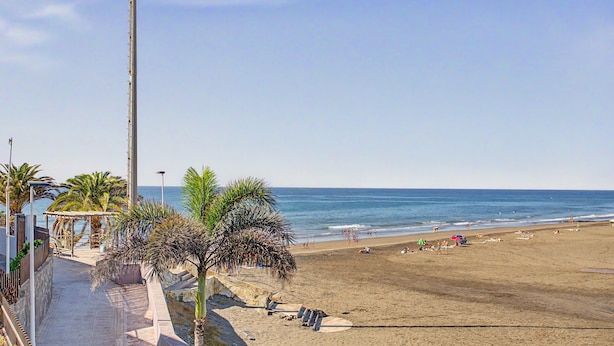 A beach with a clear sky, palm trees, and a view of the ocean. - Nueva Suecia 805 – Beachfront Apartment with Terrace and Sea Views (San Bartolomé de Tirajana)
