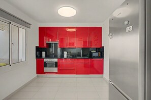 Cozinha compacta com armários vermelhos, forno embutido e micro-ondas.