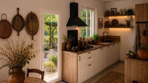 A kitchen with a central island, wooden cabinets, and a black range hood. - Maison du Vaquero - Malaga Estate - New Property (Eygalières)