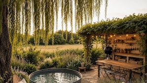 A garden with a hot tub, wooden furniture, and a pergola with string lights. - Maison du Vaquero - Malaga Estate - New Property (Eygalières)