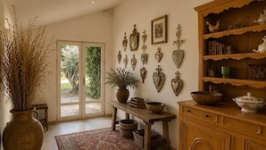 A room with a wooden cabinet, a table with a vase, and a patterned rug. - Maison du Vaquero - Malaga Estate - New Property (Eygalières)