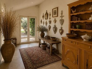 A room with a wooden cabinet, a table with a vase, and a patterned rug.