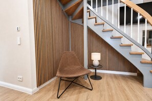 Un intérieur moderne avec un mur à lattes de bois, une chaise, une lampe et un escalier.