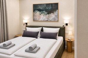 Ein Hotelzimmer mit einem Bett, zwei Nachttischen, einem Bild an der Wand und einem Vorhang.