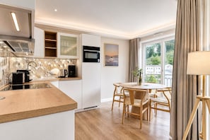 Eine moderne Küche mit Backofen, einer Kaffeemaschine und einem Essbereich mit rundem Tisch und Stühlen.