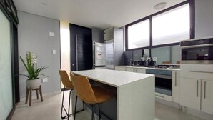 A modern kitchen with a central island, bar stools, and a potted plant. - Ntomb'lele Ocean View Luxury Villas (Tugela Mouth)