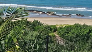 A beach with a clear view of the ocean, a sandy shore, and some greenery in the foreground. - Ntomb'lele Ocean View Luxury Villas (Tugela Mouth)