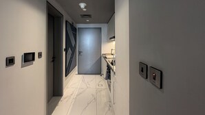 A modern hallway with a marble floor, a door with geometric patterns, and a kitchen area with a sink and cabinets. - Canal View Studio Near Dubai Mall (Dubai)