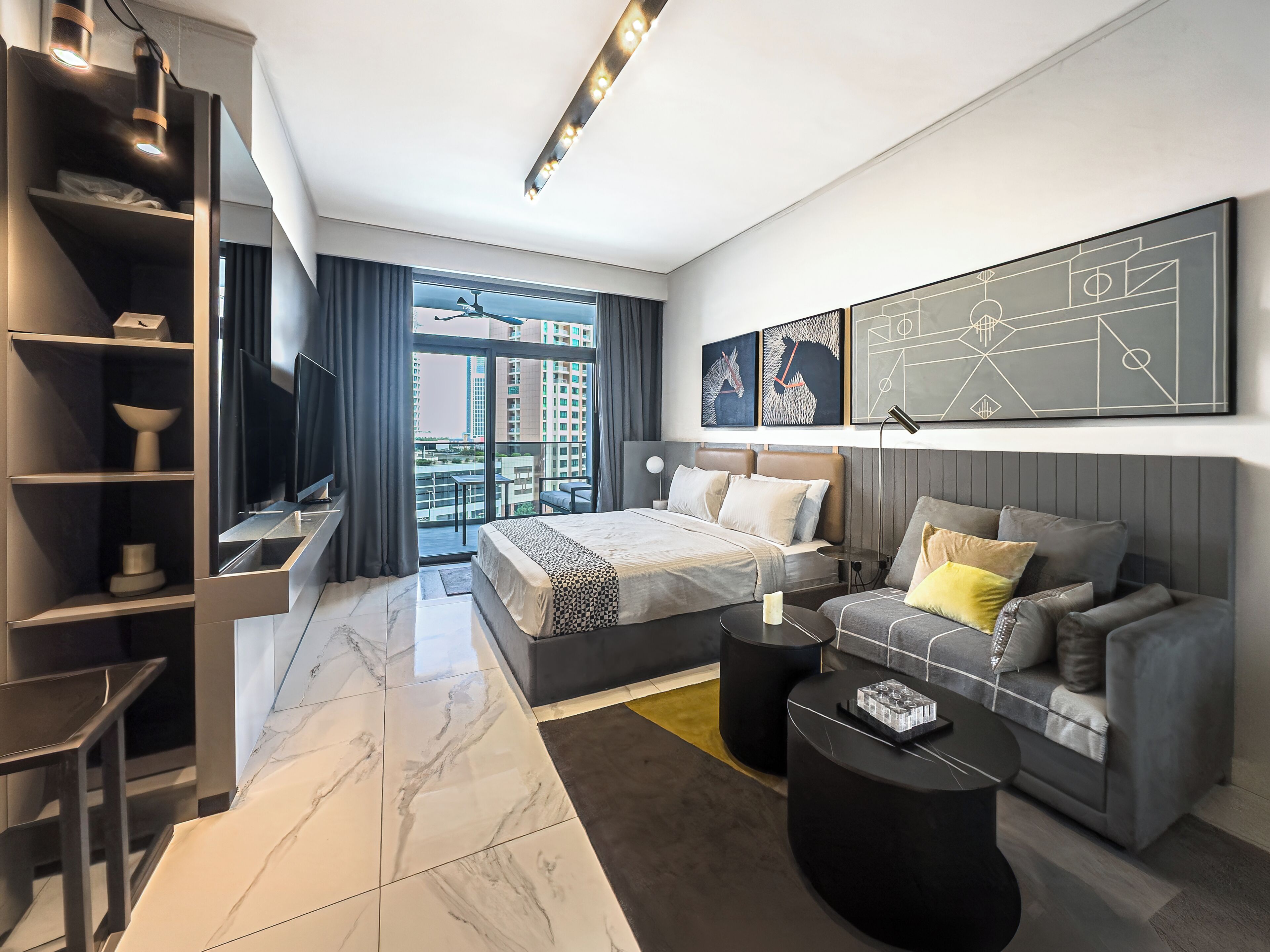 Ein modernes Hotelzimmer mit Bett, Sofa und einem Balkon mit Blick auf die Stadt.