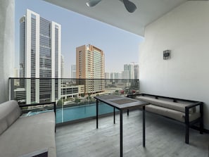 A balcony with a view of high-rise buildings, a pool, and a seating area with a table. - Canal View Studio Near Dubai Mall (Dubai)