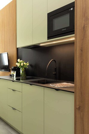 Eine moderne Küche mit Einbau-Mikrowelle, Spüle aus Edelstahl und Wandverkleidung aus Holz.
