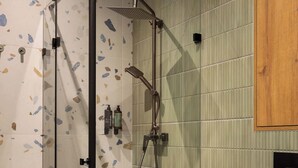 A modern bathroom with a glass shower enclosure, a toilet, and a green tiled wall. - Pułaskiego 7C | Perfect for Couples | AC (Kraków)
