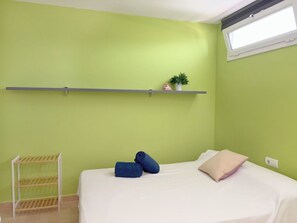 A room with a bed, a shelf with decorative items, and a window. - Apartment Clara by Interhome (St Antoni de Calonge)